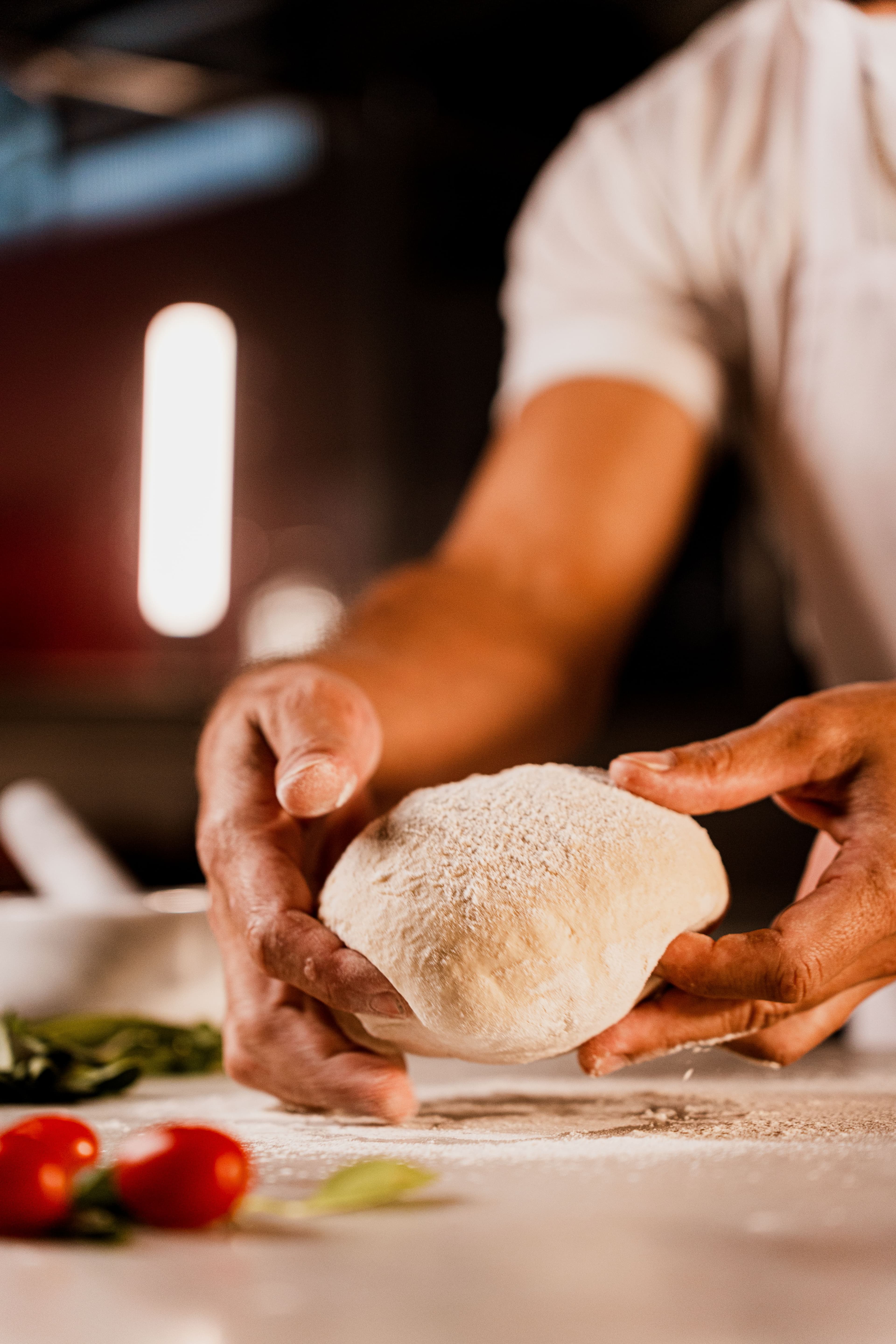 Mãos do chef abrindo a massa com amor